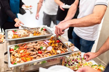 Isınma tepsisinden deniz ürünlerini kepçeleyen adam. Yemek büfesi..