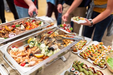 Self service buffet catering table in hotel with people serving themselves clipart