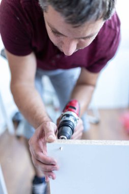 Ahşap mutfak rafı elementleri yerleştirirken elektrikli batarya matkabını kullanan adama yaklaş