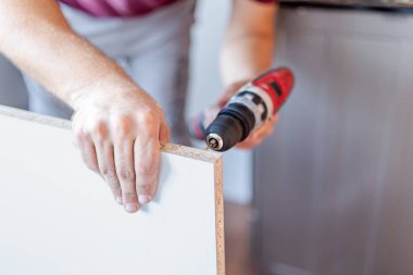 Ahşap mutfak rafları yerleştirilirken elinde elektrikli pil matkabı tutan adama yaklaş