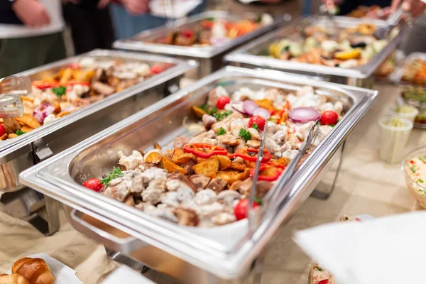 Warming tray with food and people in the background. Party lunch or dinner concept.