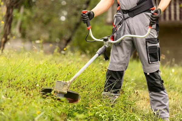 stock image Male gardener mows the green grass of the lawn in the backyard with cordless mower.