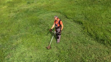 Koruyucu giysiler içinde çimleri fırçayla biçen işçilerin hava görüntüsü