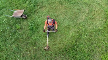 Koruyucu giysiler içinde çim biçme makinesiyle çim biçen işçilerin havadan görünüşü