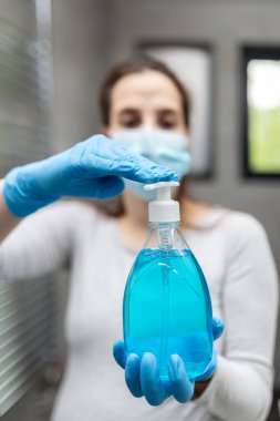 Koruyucu maske takan hamile kadın portresi ve mavi sıvı sabunla eldiven. Hijyen kavramı.