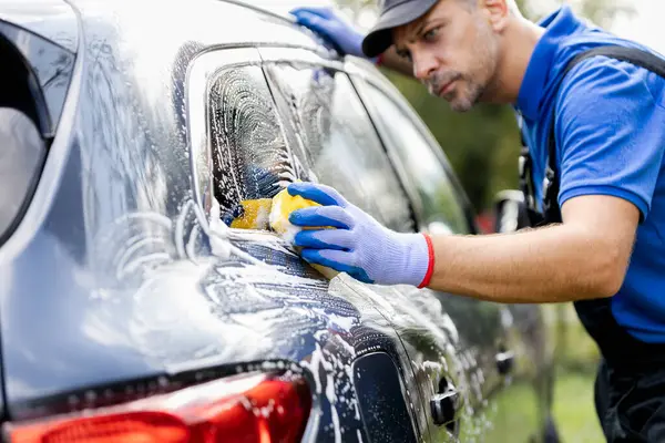 Araba yıkama işçisi araba yıkama ve sabunlama işi sarı süngerle.