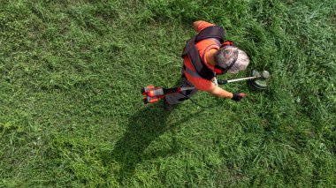Koruyucu giysiler içinde çim biçme makinesiyle çimleri kesen işçilerin havadan görünüşü