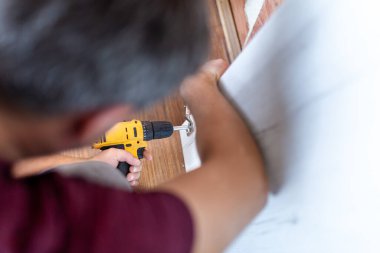 Elinde kablosuz tornavida tutan adama yakın dur ve evde bir vida montajlama için vida yalan söylüyor