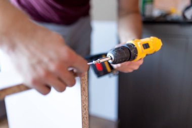 Handyman at work. Repairing kitchen shelves with cordless screwdriver