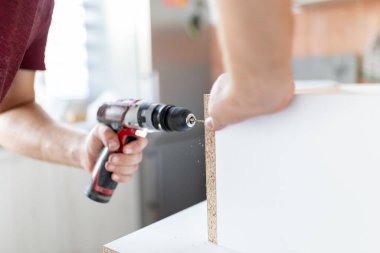 Man installing new furniture at his home and using cordless screwdriver