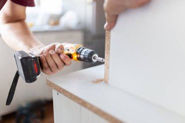 Mutfak ahşap elementlerini kablosuz tornavida matkabıyla birleştiren işçi ellerini kapatın..