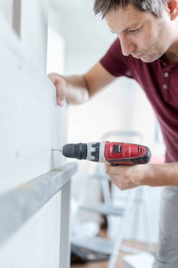 Marangoz elektrikli matkap kullanarak çekmecelerden mutfak sandığı kuruyor. Ev yenileme konsepti.