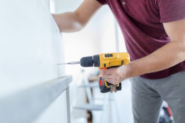 Marangoz elektrikli tornavida kullanarak çekmecelerden mutfak sandığı kuruyor. Ev yenileme konsepti.