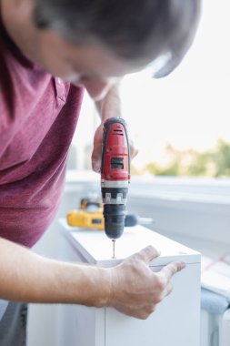 Marangoz elektrikli matkap kullanarak çekmecelerden mutfak sandığı kuruyor. Ev yenileme konsepti.