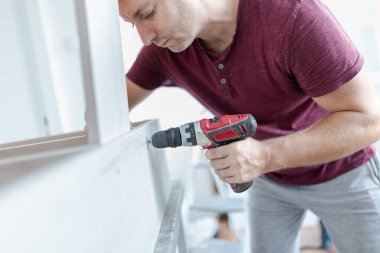 Marangoz elektrikli matkap kullanarak çekmecelerden mutfak sandığı kuruyor. Ev yenileme konsepti.