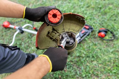 Adam çim biçme mekanizmasını kontrol ediyor..