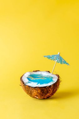 Yüzme havuzlu hindistan cevizi ya da deniz suyu ve sarı arka planda kağıt şemsiye, asgari yaratıcı kavram.