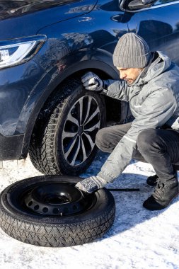 Karlı yolda lastiği yedek lastikle değiştiren adama yaklaş..