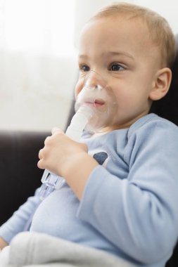 Küçük çocuk evde nebulizörle solunum yapıyor. çocuk astım spreyi soluma nebulizer buhar tutması öksürük konsepti yatay