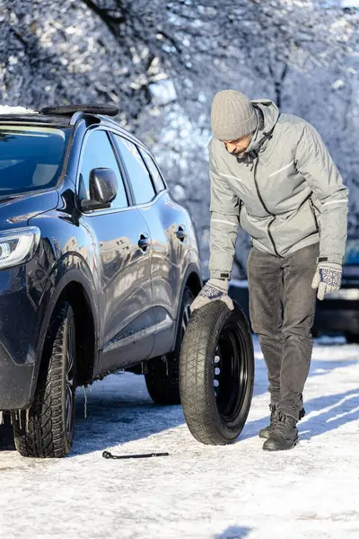 Dışarıda yedek lastiği olan bir adam var. Kış sahnesi. Patlak lastik kavramı.