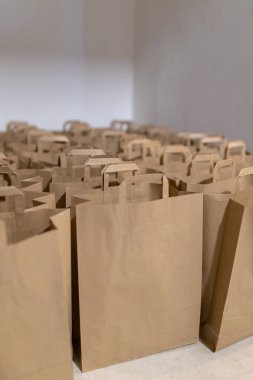 Açık renkli bir odada, temiz ve minimalist estetik eşyalar, hediyeler veya etkinlik hazırlıkları için sayısız düz kahverengi kese kağıdı düzenlenir..