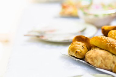 Masaya çeşitli taze ekmek ve hamur işleri sergileniyor. Misafirleri, hafta sonu brunch 'larının sıcaklığını tatmaya davet ediyorlar..