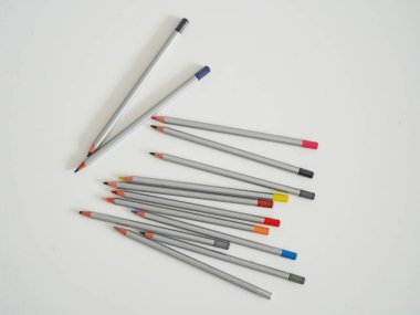 Beyaz arkaplana saçılmış renkli uçlu gri renkli kalemler. Sanat, eğitim, tasarım ve yaratıcılık kavramları için mükemmel. Okul malzemeleri, sanatsal projeler veya kırtasiye temaları için ideal.