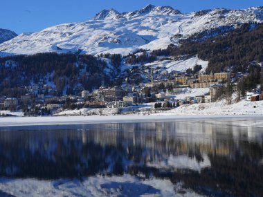 İsviçre, St. Moritz 'in nefes kesici kış manzarası. Karla kaplı dağlar, lüks dağlık oteller ve kısmen donmuş bir göl manzarayı yansıtıyor..