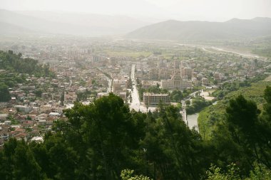 Geleneksel evleri dolambaçlı bir nehir boyunca uzanan tarihi bir Arnavut kasabasının havadan görünüşü.
