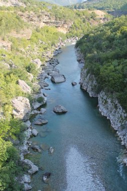 Derin bir kanyonun nefes kesen manzarası. Yüksek uçurumlar ve yemyeşil sularda süzülen bir turkuaz nehri..