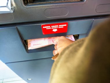 Bir el ATM makinesinden para alır.