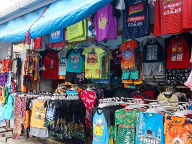 Çeşitli kıyafet ve tişörtler satan bir tezgah.