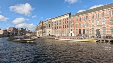Turist teknesi Amsterdam 'ın merkezindeki su kanalına çıkıyor.