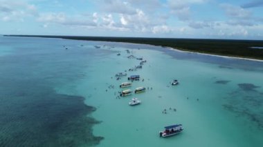 Turistler El Cielo kumsalında park etmiş sürat teknelerinin yanında dinleniyorlar. Cozumel, Meksika