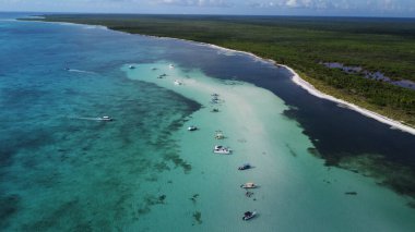 Turistler El Cielo kumsalında park etmiş sürat teknelerinin yanında dinleniyorlar. Cozumel, Meksika
