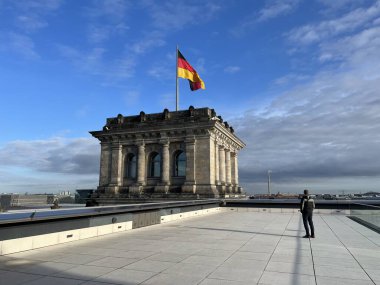 Berlin 'deki bir binanın çatısında Alman bayrağını izleyen bir adam var. Yüksek kalite fotoğraf