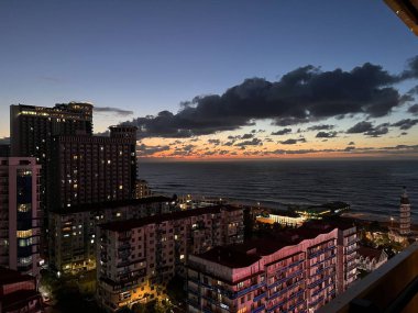 Karadeniz, güzel bir gün batımı, yüksek binalar, bulutlar ve Gürcistan 'daki Batumi şehrinin seti.