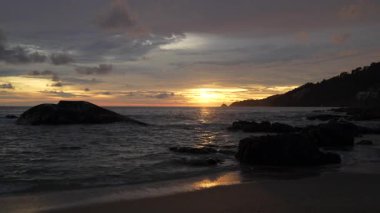 Sahilde güzel bir gün batımı. Sahilde dalgalar. Büyük kayalar. Phuket Adası. Yağmur mevsimi. Tayland