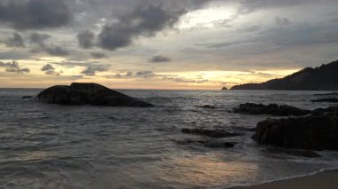 Sahilde güzel bir gün batımı. Sahilde dalgalar. Büyük kayalar. Phuket Adası. Yağmur mevsimi. Tayland