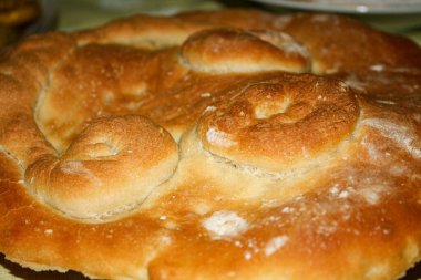 Fırından yeni çıkmış nefis taze ekmek. Süslü pide stili ekmek. Bu ağız sulandırıcı fotoğraf taze pişmiş ekmeğin karşı konulmaz cazibesini yakalar, sıcak ve güzel kokulu bir evden ortaya çıkar.