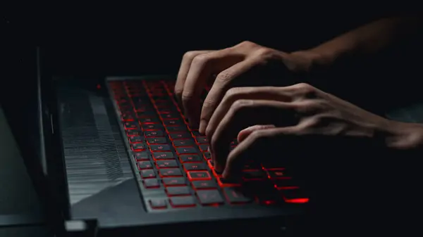 Close-up of a man's hands typing on a gaming laptop. playing games