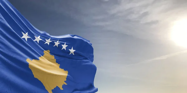 stock image Kosovo national flag cloth fabric waving on beautiful grey sky Background.