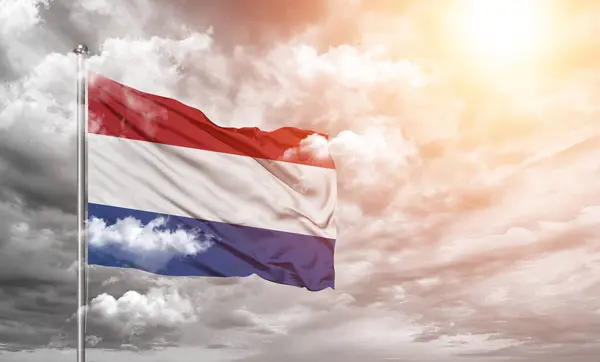 荷兰国旗布织物在美丽的云彩灰色背景上飘扬 — 图库照片