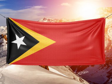 Doğu Timor (Timor-Leste) Ulusal bayrak kumaşı güzel dağ arka planında dalgalanıyor.