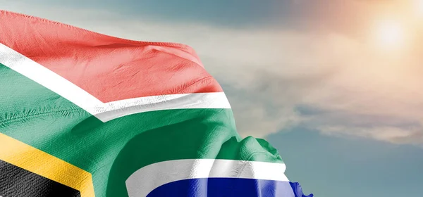 South Africa national flag cloth fabric waving on beautiful sky Background.