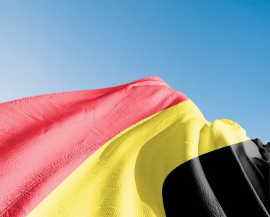 Güzel Gökyüzü Arkaplanı 'nda sallanan Belçika bayrağı kumaşı.