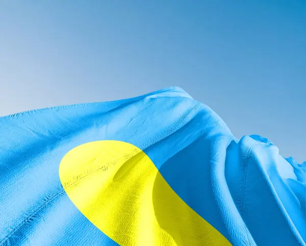 Palau Ulusal Bayrak Kumaşı Güzel gökyüzü mavi arka planda dalgalanıyor.