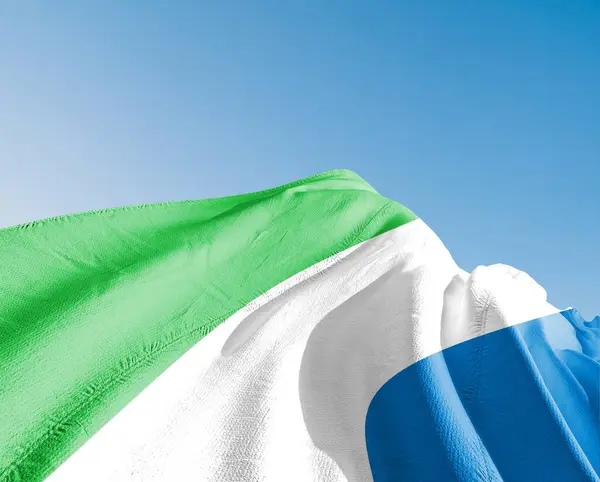 stock image Sierra Leone national flag cloth fabric waving on beautiful sky blue Background.