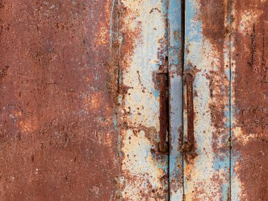 Fabrikadaki eski paslı metal kapılar kapalı. Kırmızı-turuncu paslı tüplerden yapılmış uzun sapları kapatın..