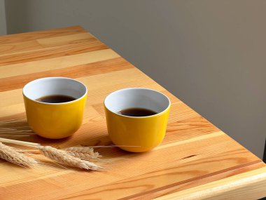 İki sarı fincan ve ahşap masada sıcak kahve. 